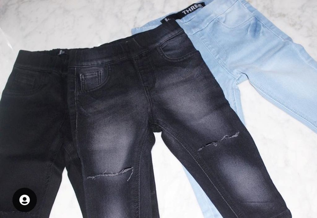 Black and light blue THE UNKNOWN CHILDREN jeans on a white surface