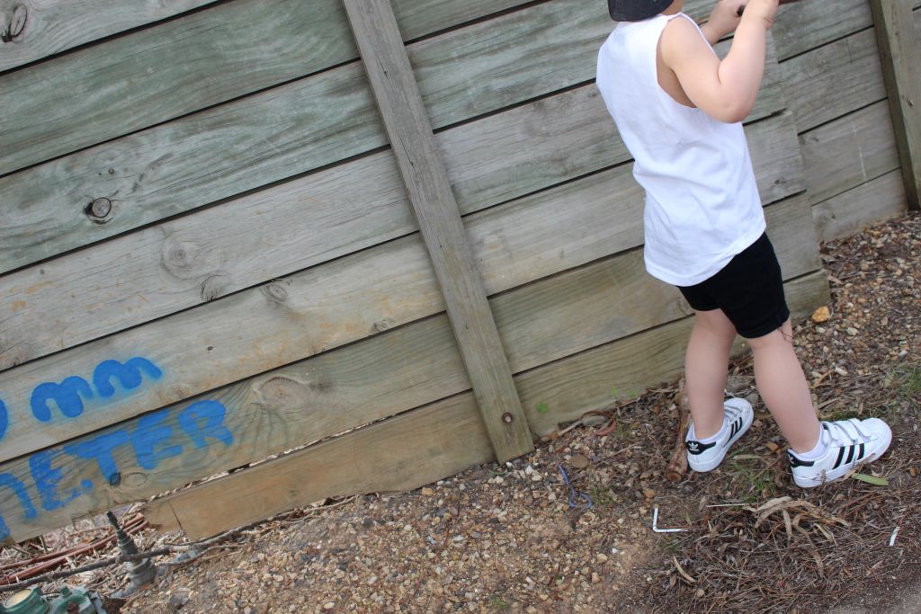 Child wearing a white singlet paired with black rolled hem denim shorts and white
sneakers. The outfit offers a casual and stylish look for active play or everyday wear.