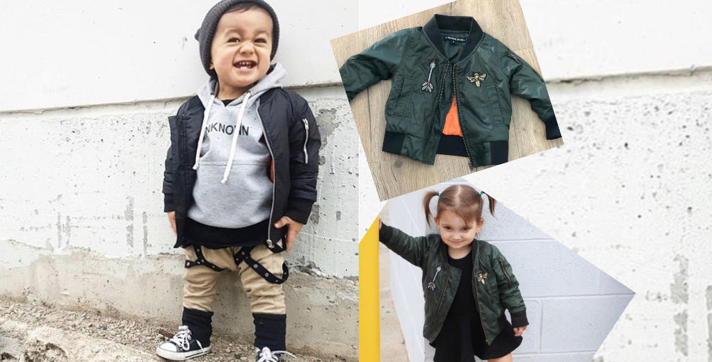 Child wearing a green jacket with a brand logo, standing against a white wall.