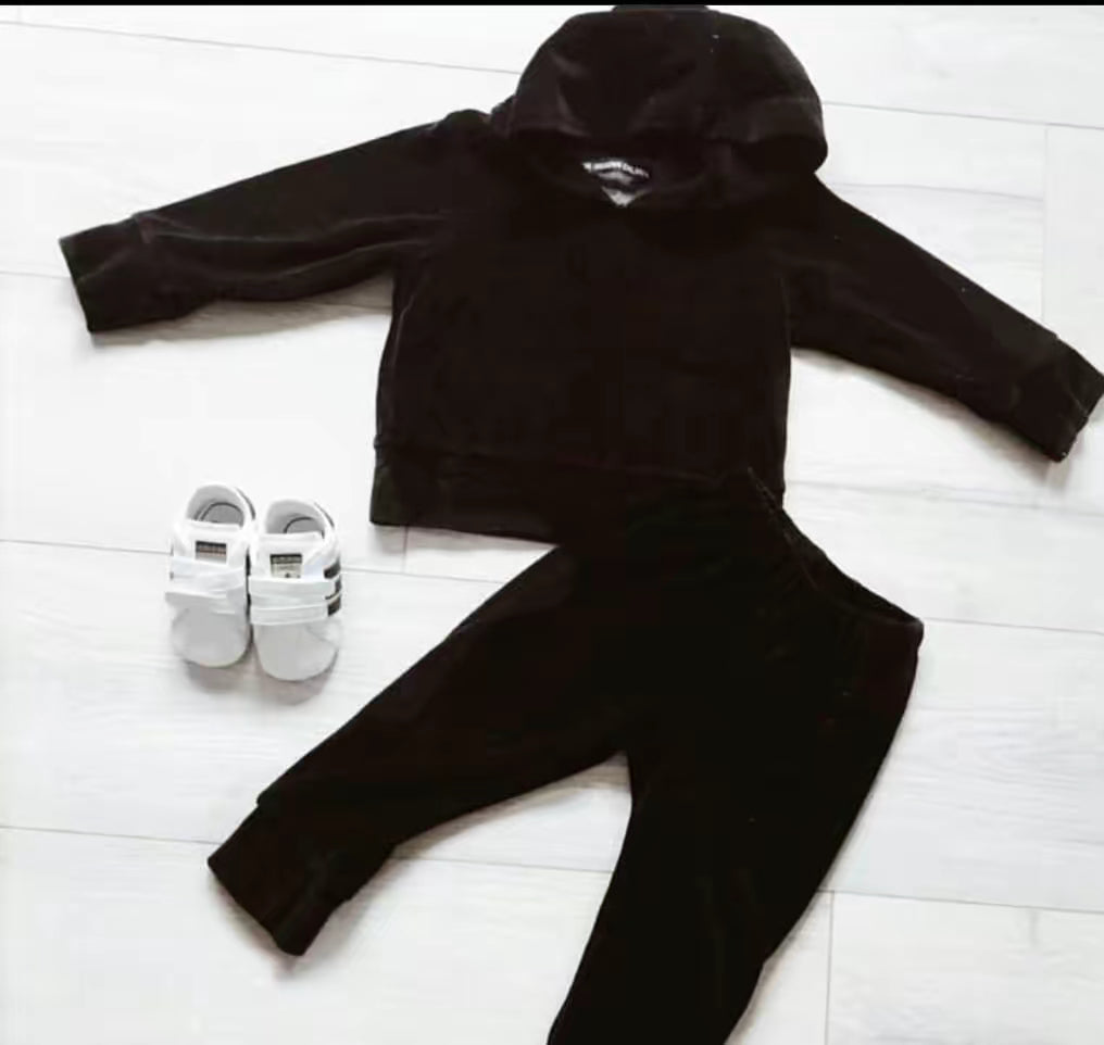 THE UNKNOWN CHILDREN "CLASSICS" Black Velvet Set, featuring a soft black velvet hoodie and matching pants, paired with white sneakers. This versatile and stylish tracksuit for girls is perfect for play or lounging.

