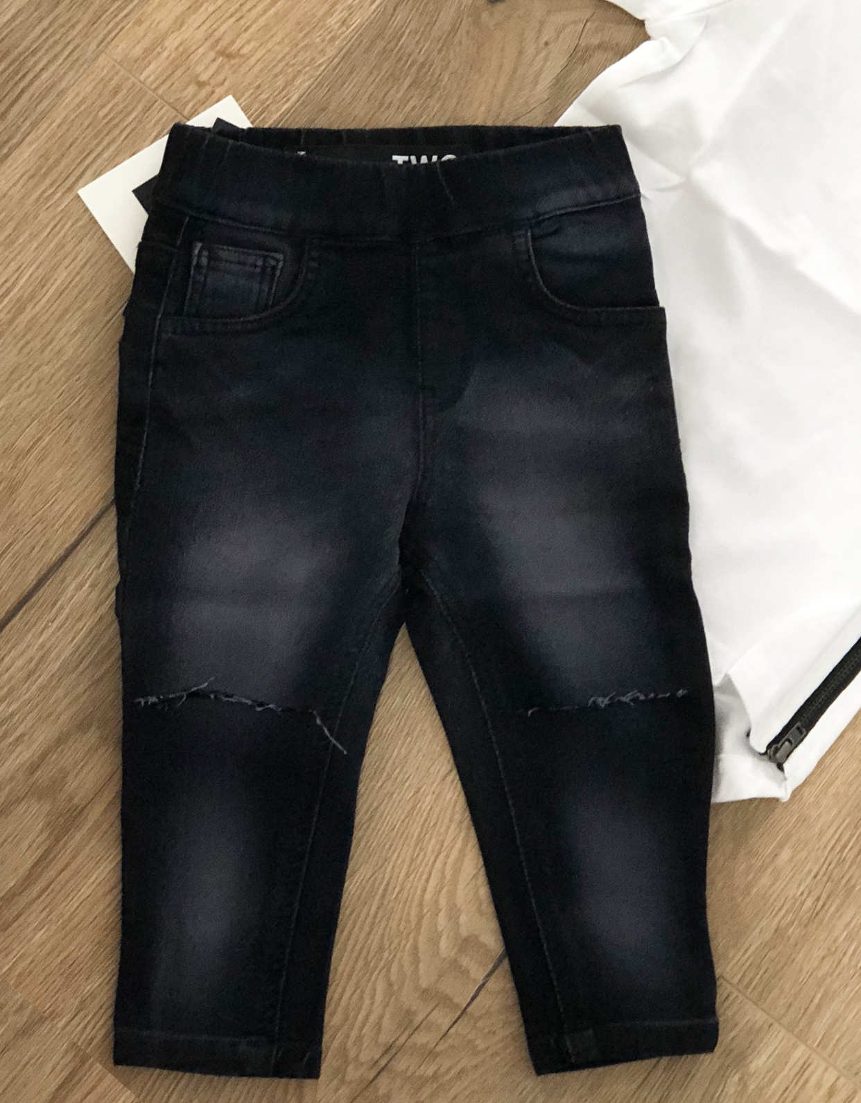Black distressed jeans on a wooden floor